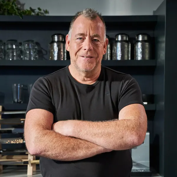 Chef with folded arms in a dark professional kitchen