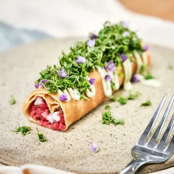 Wrap with tartare, cress and edible flowers on a stone plate