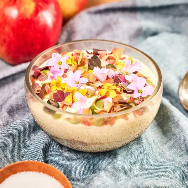 Dessert bowl finished with edible flowers, apple in the background