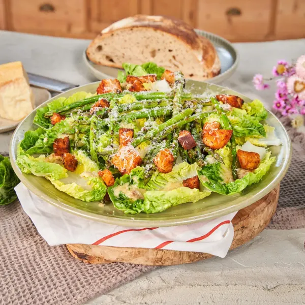 Caesar salad with croutons and grated cheese on a wooden board