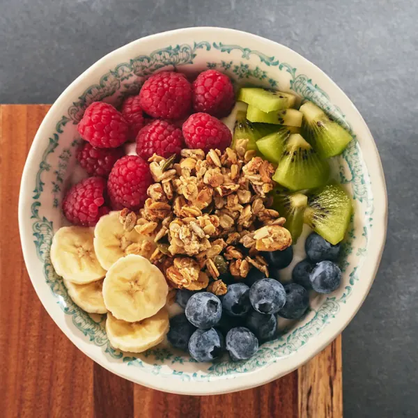 Yoghurt bowl with granola, raspberries, banana, kiwi and blueberries