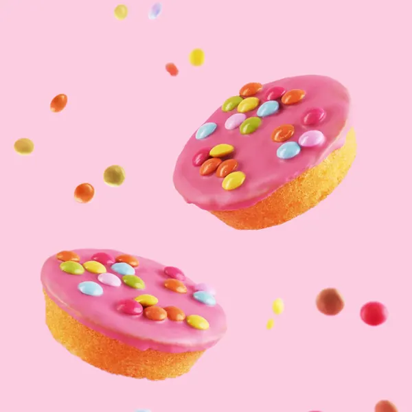 Two pink glazed cakes with sprinkles against a pink background
