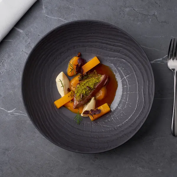 Pasta with pumpkin and a herb crust on a dark plate