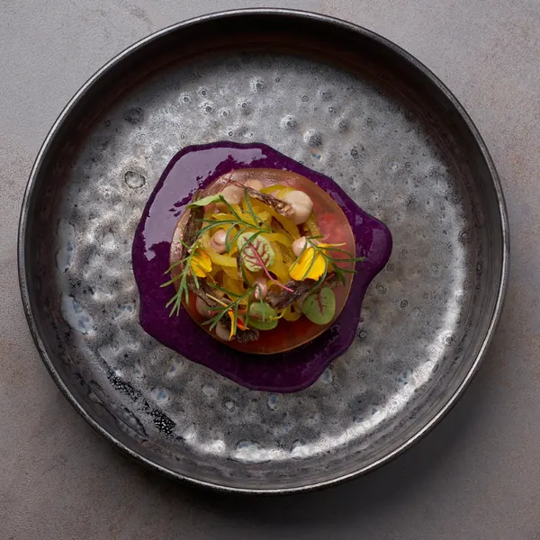 Dish on beetroot puree in a dark pan, seen from above