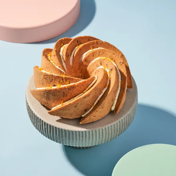 Bundt cake on a light pedestal against a blue background