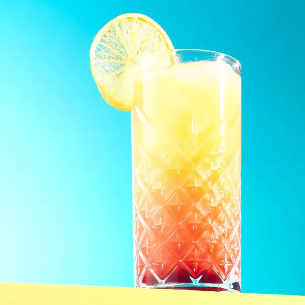 Layered cocktail with a lemon slice against a blue and yellow background